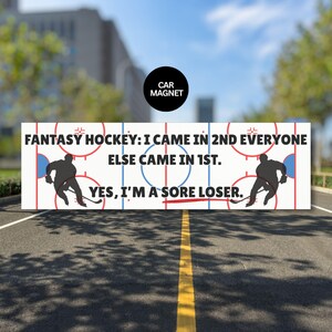 May include: A rectangular car magnet with a hockey rink design and the text "FANTASY HOCKEY: I CAME IN 2ND EVERYONE ELSE CAME IN 1ST. YES, I'M A SORE LOSER." Two hockey player silhouettes are on the sides.