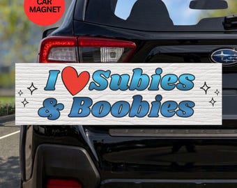 May include: A rectangular white car magnet featuring the blue text I, a red heart symbol, the word Subies, the ampersand symbol, and the word Boobies. The text has a blue gradient and black outline, accented by four small black four-pointed star icons.