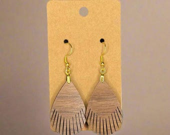 May include: A pair of teardrop-shaped wooden earrings with a fringe design. The earrings are a medium brown colour and hang from gold-coloured hooks. They are displayed on a brown card.