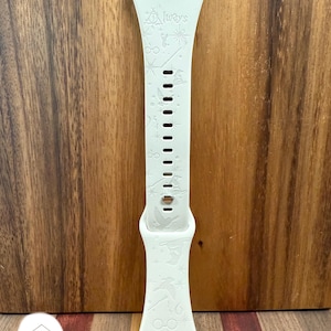 Peut inclure: Bracelet de montre en silicone blanc avec un motif en relief blanc et gris représentant des symboles d'Harry Potter et les mots "Always".