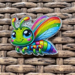 May include: A colorful cartoon bee with a glittery outline. The bee has a green head, blue eyes, and rainbow wings. Its body is striped with various colors. The image is set against a woven background.