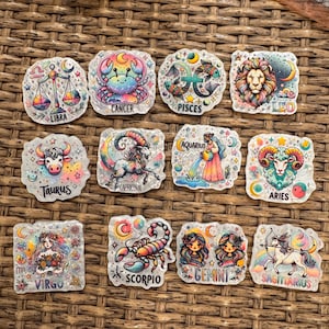 May include: A collection of twelve colorful zodiac sign stickers. Each sticker features a unique illustration of the zodiac symbol, name, and associated imagery. The stickers are in various colors, including pink, blue, yellow, and green.