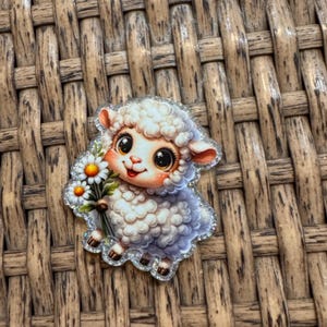 May include: A cute, glittery sheep sticker holding a bouquet of daisies. The sheep has large, expressive eyes and a smiling face. The sticker has a white, fluffy body and is outlined with silver glitter. The daisies have white petals and yellow centers.