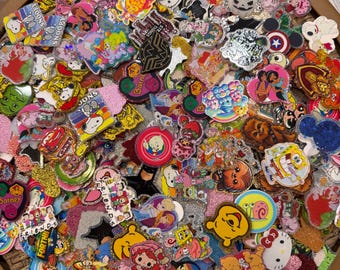 May include: A large collection of assorted acrylic character pins and charms featuring various pop culture icons, including Snoopy, Winnie the Pooh, SpongeBob SquarePants, and Hello Kitty, with glittery finishes and vibrant, multi-colored designs.