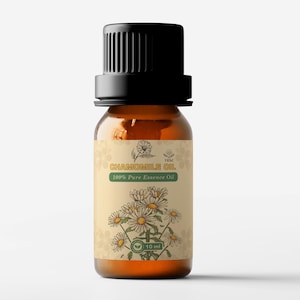 Op de afbeelding: Een bruine glazen fles kamille-olie met een zwarte dop. Het etiket toont een illustratie van een kamillebloem en de tekst "Chamomile Oil 100% Pure Essence Oil". De fles bevat 10 ml olie.
