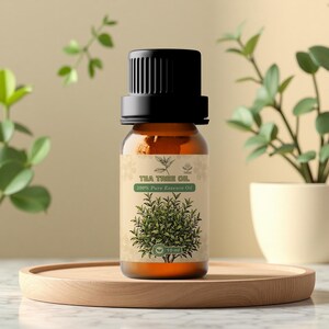 Könnte beinhalten: Kleine bernsteinfarbene Glasflasche mit Teebaumöl und schwarzem Deckel. Das Etikett trägt die Aufschrift "Tea Tree Oil 100% Pure Essence Oil" und zeigt eine grüne Abbildung eines Teebaums. Die Flasche steht auf einem Holztablett.