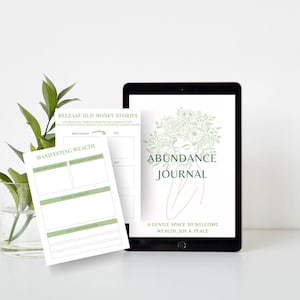 May include: A digital tablet displaying a cover page titled Abundance Journal with a line drawing of a person with flowers, alongside a printed page titled Manifesting Wealth and Release Old Money Stories with green accents and text fields.