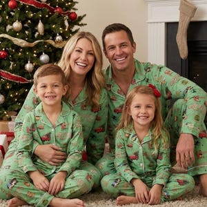Può includere: Una famiglia di quattro persone indossa pigiami natalizi verdi abbinati con una stampa festiva. Sorridono davanti a un albero di Natale decorato. I pigiami hanno una parte superiore abbottonata e pantaloni.