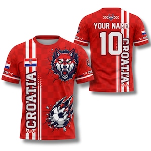 May include: Red Croatia soccer jersey with a wolf graphic breaking through a wall. The front features the word "CROATIA" vertically. The back has the number 10 and space for a name. The jersey has the Croatian flag on the sleeves.