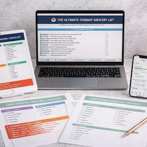 May include: A workspace setup with a laptop, tablet, and smartphone displaying a "Low FODMAP Grocery Checklist." Printed checklists and a pen are also present. The laptop screen shows "The Ultimate FODMAP Grocery List."