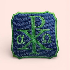 May include: Embroidered patch featuring the Chi Rho symbol in green on a blue background. The patch has a green border and a shield shape. The Greek letters alpha and omega are also visible.