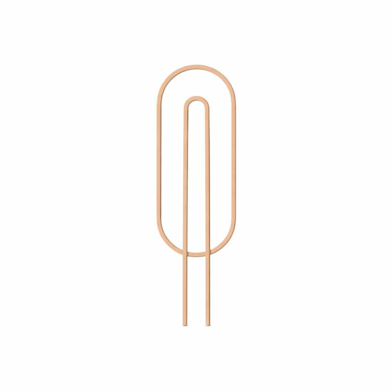 May include: A light brown, abstract metal sculpture with a vertical, elongated oval shape. Two parallel lines extend downward from the oval, creating a minimalist design. The sculpture is set against a white background.