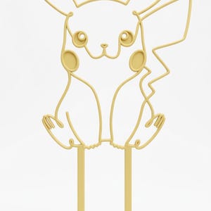 May include: A light yellow cake topper featuring a continuous line art design of a cartoon creature with long pointed ears, circular cheeks, and a jagged tail. The figure is supported by two vertical prongs extending from the base of the design.