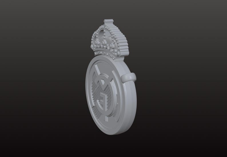 May include: A grey, three-dimensional emblem featuring a crown above a circular design. The circular design has a central graphic and a surrounding ring. The emblem is set against a dark grey background.