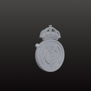 May include: A grey, three-dimensional emblem featuring a crown above a circular design. The circular design has a striped pattern and a smaller emblem in the centre. The emblem is set against a dark background.