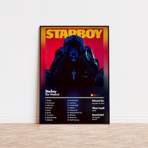 May include: A framed poster for The Weeknd's album "Starboy." The artwork features a blue-toned image of a person with hands on their head, a cross pendant, and the album title in yellow. The poster includes a tracklist and album details.