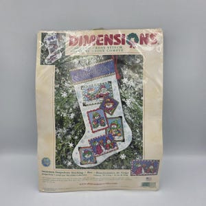 May include: A Dimensions cross-stitch kit for a snowman-themed Christmas stocking. The white stocking has a blue cuff and features cross-stitched images of snowmen. The kit includes the name "Harrison".