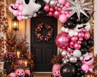 May include: A balloon arch framing a black door, featuring pink, black, white, and silver balloons, a large ghost-shaped balloon, a silver starburst balloon, and small black bat cutouts. Pink pumpkins and lanterns sit on the porch floor.