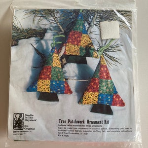 Może przedstawiać: Zestaw do rękodzieła do wykonania trzech ozdób choinkowych w stylu patchwork. Zestaw zawiera tkaniny bawełniane, wypełnienie z poliestru, filc i instrukcje. Ozdoby mają 12,7 cm wysokości. Kit #773K.