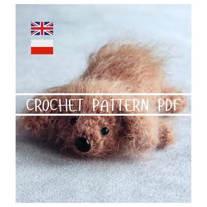 Può includere: Un orsacchiotto all'uncinetto marrone fatto a mano con occhi a bottone neri e un naso nero. Il testo "CROCHET PATTERN PDF" è visualizzato sull'immagine. L'orso è sdraiato su una superficie grigio chiaro.
