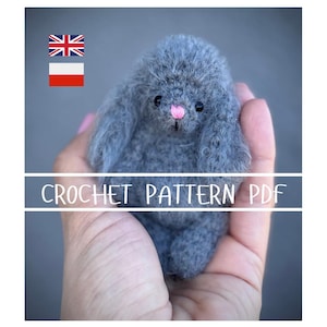 Może przedstawiać: Mały, szary szydełkowy króliczek z oklapniętymi uszami i różowym noskiem. Tekst "CROCHET PATTERN PDF" jest wyświetlany na białym banerze. Obraz zawiera również flagi Wielkiej Brytanii i Polski.