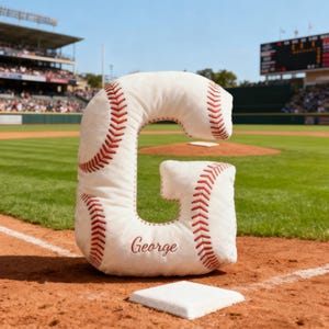 Cojín personalizado con inicial y nombre bordado, ideal para amantes del béisbol.