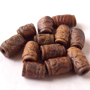 May include: A group of brown ceramic beads with intricate designs. The beads are cylindrical and have a rough, textured surface.