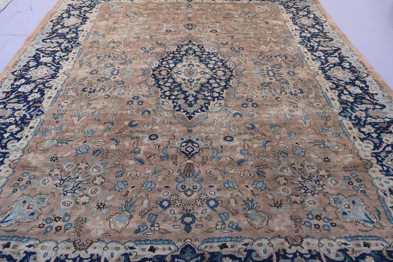 K&ouml;nnte beinhalten: Ein gro&szlig;er, rechteckiger Teppich mit einem komplizierten floralen Design. Der Teppich hat ein zentrales Medaillon in Marineblau, umgeben von einem Feld aus beige- und hellblauen Blumenmustern. Der Rand ist dunkelmarineblau mit floralen Motiven.