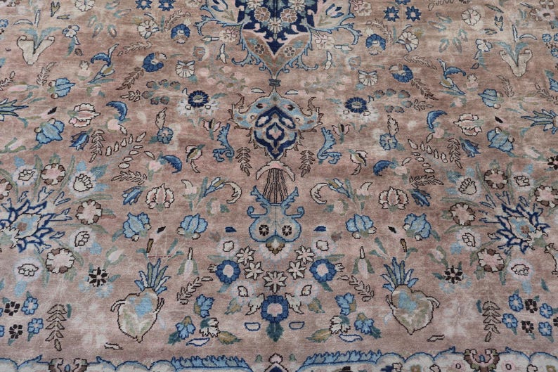 K&ouml;nnte beinhalten: Nahaufnahme eines Teppichs mit floralem Muster. Der Teppich hat einen beigefarbenen Hintergrund mit blauen und cremefarbenen Blumenmotiven. Das Design umfasst stilisierte Blumen und Bl&auml;tter.
