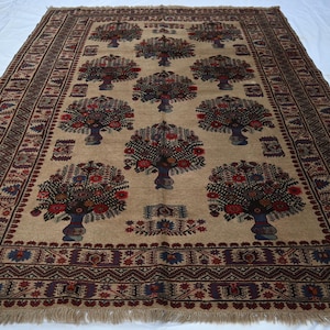 May include: Beige rectangular rug featuring a repeating tree of life pattern. The trees are adorned with red, brown, and blue floral details. The border has geometric designs in brown and blue, with a fringed edge.