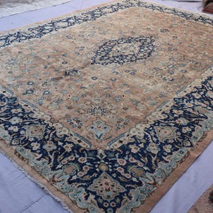 K&ouml;nnte beinhalten: Ein gro&szlig;er, rechteckiger Teppich mit einem aufwendigen floralen Design. Der Teppich hat ein zentrales Medaillon und einen Rand in den Farbt&ouml;nen Marineblau, T&uuml;rkis und Beige. Der Teppich ist wahrscheinlich aus Wolle und eignet sich f&uuml;r ein Wohn- oder Schlafzimmer.
