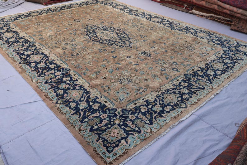 K&ouml;nnte beinhalten: Gro&szlig;er, rechteckiger Teppich mit einem aufwendigen Blumenmuster. Der Teppich hat ein zentrales Medaillon in Blau und Beige, umgeben von einem marineblauen Rand mit floralen Mustern. Die Farbgebung des Teppichs ist dezent, was ihm ein Vintage-Aussehen verleiht. Ca. 300 x 200 cm.