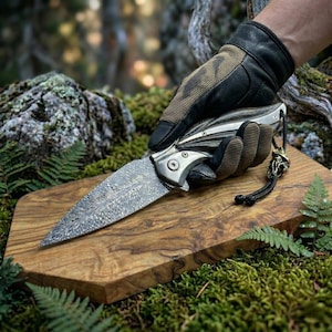 May include: A white ceramic mug with a black handle and the text "But First, Coffee" in a bold, black font. The mug is set against a blurred background, suggesting a cozy setting.