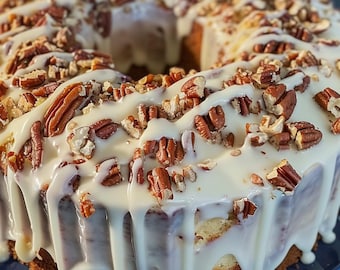 May include: A ring-shaped cake with a white glaze and pecan topping. The glaze is drizzled over the cake, and the pecans are scattered on top. The cake sits on a blue plate.