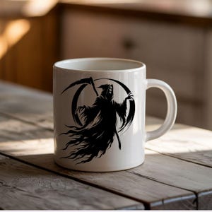 May include: White ceramic mug featuring a black graphic of the Grim Reaper with a scythe. The design is set against a black circular background. The mug has a curved handle and is placed on a wooden surface.