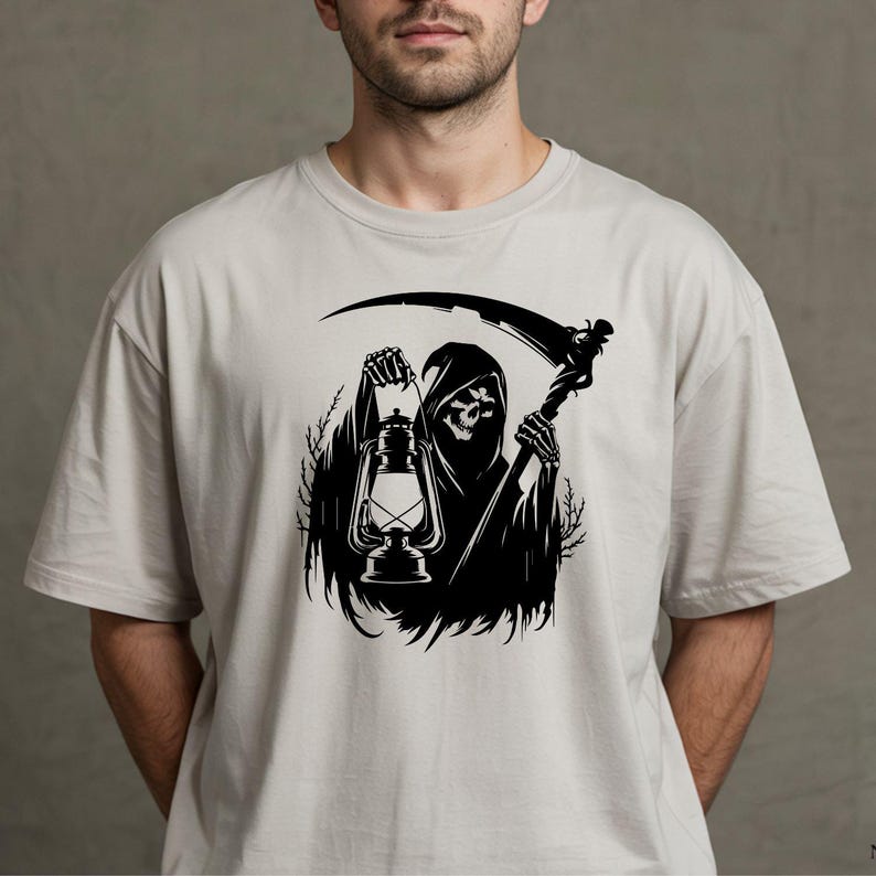 May include: A light gray t-shirt featuring a black graphic of the Grim Reaper holding a lantern and a scythe. The Grim Reaper is depicted in a hooded cloak with a skull face. The design is centered on the shirt.