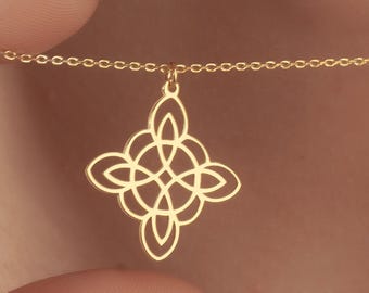 Op de afbeelding: Een goudkleurige ketting met een Keltische knoop hanger. De hanger is een symmetrisch, open ontwerp dat aan een delicate ketting hangt. De ketting wordt gepresenteerd tegen een huidskleurige achtergrond.