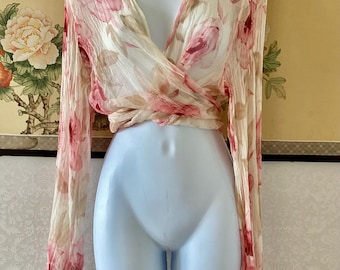 Blusa elegante rosa transparente con estampado floral y lazo.