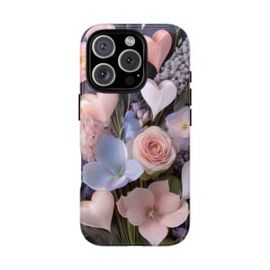 Op de afbeelding: Een telefoonhoesje met een bloemenpatroon, met roze, witte en blauwe bloemen en hartvormige accenten. De hoes heeft een glanzende afwerking en een donkere achtergrond, met een uitsparing voor een drievoudige cameralens.