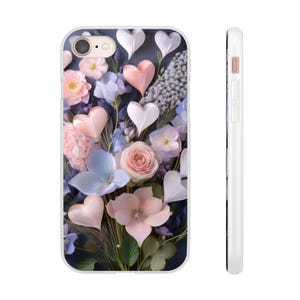 Op de afbeelding: Een witte telefoonhoes met een bloemenontwerp met roze, witte en blauwe bloemen en hartvormige accenten. De hoes heeft een glanzende afwerking en een camera-uitsparing. De zijaanzicht toont een slank profiel.