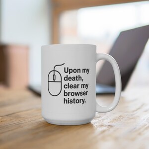 Könnte beinhalten: Weiße Keramiktasse mit schwarzer Umrandung einer Computermaus und dem Text "Upon my death, clear my browser history." Die Tasse hat einen großen Henkel und steht auf einer Holzoberfläche.