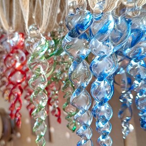 May include: A collection of glass baubles in various colours, including red, green, and blue. The baubles are twisted and spiral in shape, resembling icicles.
