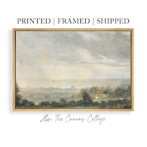 May include: A framed landscape painting with a light wood frame. The artwork depicts a serene countryside scene with a cloudy sky, rolling hills, and trees. The text "PRINTED | FRAMED | SHIPPED" is at the top. The Canvas Cottage logo is at the bottom.