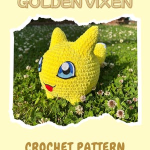 Op de afbeelding: Een gehaakt geel wezen met blauwe en witte ogen, een rode mond en puntige oren, rustend in gras en klaver. De afbeelding bevat de tekst "GOLDEN VIXEN" en "CROCHET PATTERN By Little Bunny Garden."