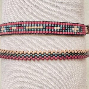 May include: Two beaded bracelets. The top bracelet has a pattern of red, teal, and beige beads. The bottom bracelet has a similar design, with red, beige, and teal beads. Both bracelets are displayed on a neutral fabric background.