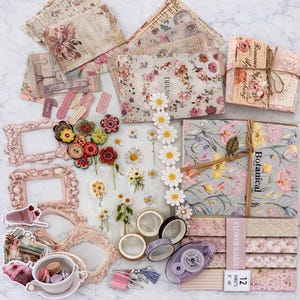 May include: A selection of vintage-style scrapbooking items, including floral patterned paper, decorative frames, washi tape, and embellishments. The colour scheme features soft pinks, creams, and greens, with daisy and floral accents. The word "Botanical" is visible on a journal.