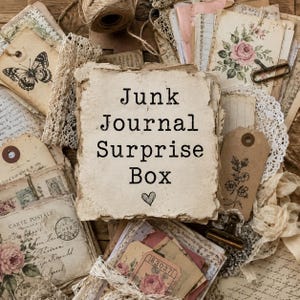 May include: A collection of vintage ephemera, including aged paper, tags, lace, and floral accents, arranged around a central piece of paper with the text "Junk Journal Surprise Box" and a heart symbol. The items are in shades of cream, brown, and pink.
