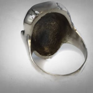 Pu&ograve; includere: Anello d'argento con un design a forma di teschio. L'anello &egrave; mostrato dall'interno, rivelando la fascia liscia in argento.