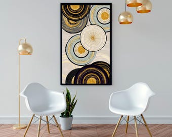 May include: Abstract art print featuring concentric circles in black, gold, and light blue hues. The artwork is framed in black and hangs on a white wall. The room is decorated with white chairs, a gold floor lamp, and pendant lights.