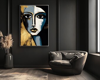 May include: Abstract portrait art print featuring a woman's face with a split design. One side is gold, the other is blue and white. The artwork is framed and hangs on a dark wall above a gray armchair.